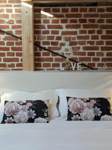 a bed with two pillows and a brick wall at La Rose des Vents - Appartement avec Terrasse, Piscine et Parking in Lautenbach
