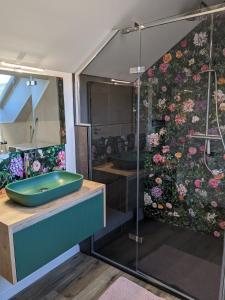 La salle de bains est pourvue d'une douche et d'une baignoire bleue. dans l'établissement Appartement La Rose des Vents, à Lautenbach