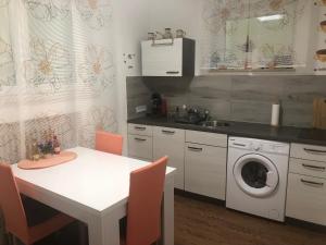 Apartment Lucy في توتلِنغين: مطبخ مع طاولة بيضاء وغسالة ملابس