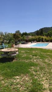 una mesa de picnic en el césped junto a una piscina en T2 au calme avec piscine, en Néoules