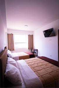 タクナにあるBruan Hotelのベッド2台とテレビが備わるホテルルームです。