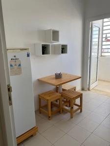 a kitchen with a wooden table and a refrigerator at Appartement simple et propre in Sfax