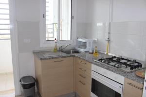 a white kitchen with a sink and a stove at Appartement simple et propre in Sfax