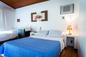 um quarto com uma cama com um edredão azul em Pousada Pontal da Praia em São Pedro da Aldeia