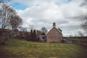 une petite maison en briques sur un champ herbeux dans l'établissement Castle Cottage, Press Mains Farm Cottages, à Eyemouth