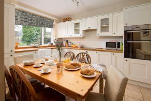 une cuisine avec une table en bois et des chaises ainsi qu'une salle à manger dans l'établissement Castle Cottage, Press Mains Farm Cottages, à Eyemouth