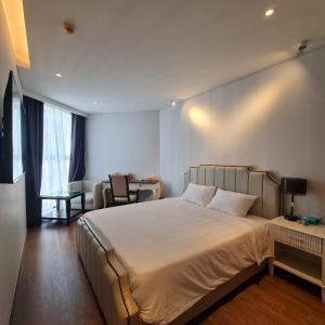 a bedroom with a large white bed and a desk at Apec Mandala Cham Bay Mui Ne in Ấp Thiẹn Ái