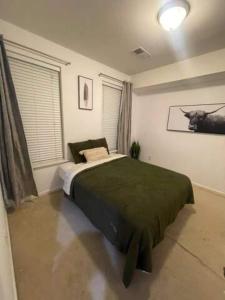 um quarto com uma cama verde num quarto com janelas em 2 Cozy Bedroom Townhome em Germantown