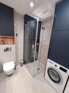 a bathroom with a shower and a toilet and a washing machine at Apartament przy tężni in Augustów +21 photos