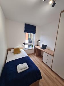 a bedroom with a bed with a blue blanket and a mirror at Apartament przy tężni in Augustów
