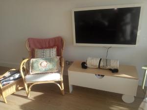 een woonkamer met een stoel en een tv bij Vittoria Immobilier 10 -Vue Dégagée - Terrasse - chèques vacances acceptés in La Grande-Motte