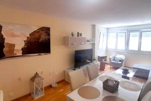 a living room with a table and a tv at Apartamento Playa Foz in Foz