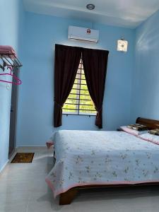 a blue bedroom with a bed and a window at Homestay Haji Noor in Tanah Merah