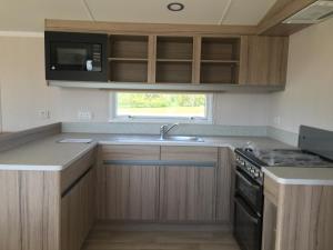 a kitchen with wooden cabinets and a sink and a microwave at Miss Grace Plot 26 in Lincoln