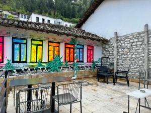 un patio con mesas y sillas y ventanas coloridas en Helin's Hostel by Backpackers en Berat