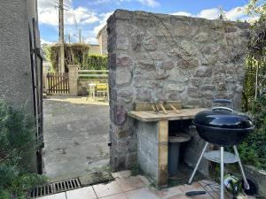a grill sitting next to a stone wall at 357 - Appartement T3 à 100m de l'Anse du Croc. in Frehel
