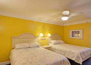 two beds in a room with yellow walls at Direct oceanfront, fantastic ocean view, separate bedroom ! - All amenities available November 1 ! in Daytona Beach +22 photos