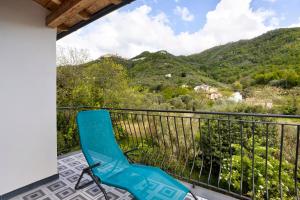 einen blauen Stuhl auf einem Balkon mit Bergen im Hintergrund in der Unterkunft Villino Marco in Luni
