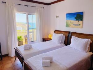 two beds in a bedroom with a view of the ocean at Benagil Beach House - Victoria in Lagoa