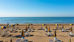 a beach with chairs and umbrellas and the ocean at The Green Park Hotel in Cavallino-Treporti