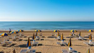 een strand met stoelen en parasols en de oceaan bij The Green Park Hotel in Cavallino-Treporti
