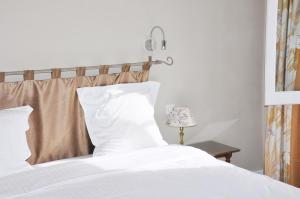 a bed with white sheets and a lamp on a table at Hôtel de France in Auch
