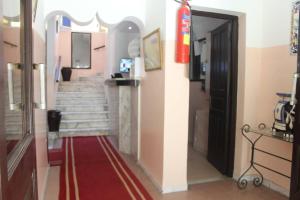 a hallway with stairs and a door with a red rug at Hotel de la plage in Bizerte