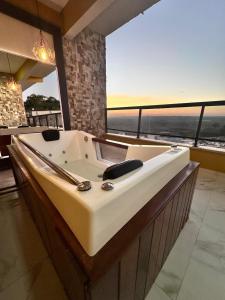 a bath tub in a room with a large window at ECOLETRAS APART - HOTEL - SÃO THOMÉ DAS LETRAS Mg in São Thomé das Letras