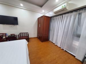 um quarto com uma cama, uma televisão e uma janela em Dodo Home 3 em Hanói