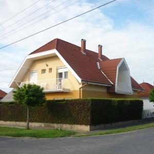 una casa amarilla con techo marrón en Farkas Apartmanok, en Balatonlelle