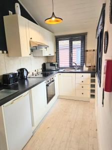uma cozinha com armários brancos e bancadas pretas em Magpie 1 Hot Tub HuntersMoon-Warminster-Bath-Wiltshire em Warminster