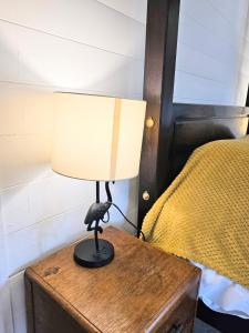 a lamp on a wooden table next to a bed at Magpie 1 Hot Tub HuntersMoon-Warminster-Bath-Wiltshire in Warminster