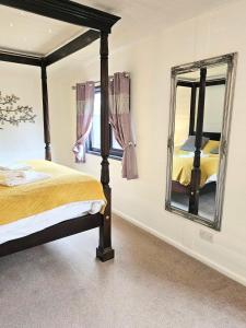 1 dormitorio con cama y espejo en Magpie 1 Hot Tub HuntersMoon-Warminster-Bath-Wiltshire, en Warminster