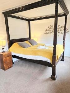 1 dormitorio con cama grande con dosel y sábanas amarillas en Magpie 1 Hot Tub HuntersMoon-Warminster-Bath-Wiltshire en Warminster