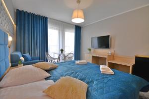 sypialnia z niebieskim łóżkiem i salon w obiekcie Apartamenty Cesarskie - Apartamenty Bryza - Parking w Świnoujściu