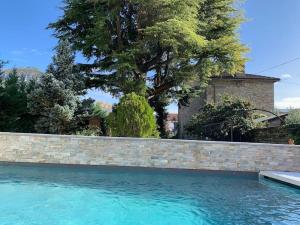 una piscina con una pared de retención y un árbol en Superbe Villa Centre-ville Millau, en Millau