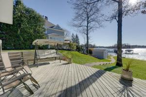 une terrasse en bois avec des chaises et un parasol ainsi qu'une maison dans l'établissement Lakeside Michigan Retreat with Boat Dock and Fireplace, à Woodland Beach