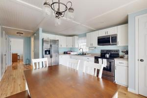 una cucina con un tavolo in legno e mobili bianchi di Mabel's Maine Cottage a Boothbay Harbor