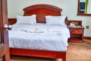 a bedroom with a large bed with a wooden headboard at Nobilis Hotel and Apartments in Kigali