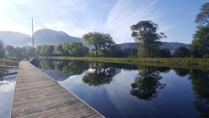 Un puente de madera sobre un río con montañas al fondo. en Neptune's Rest, en Fort William