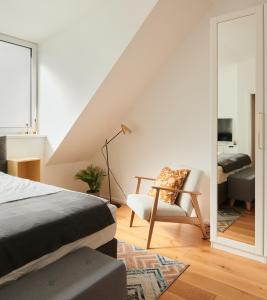 1 dormitorio con cama, silla y espejo en New Spacious Ultra-Modern Apartment in Wien Westbahnhof en Viena