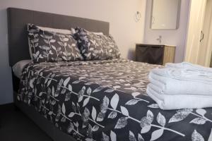 Schlafzimmer mit einem Bett mit einer schwarzen und weißen Bettdecke in der Unterkunft AMR Hotel Inc in Saint-Jérôme