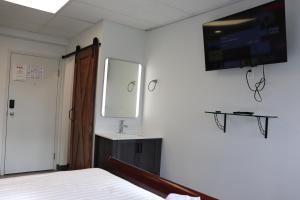 1 dormitorio con 1 cama y TV en la pared en AMR Hotel Inc en Saint-Jérôme