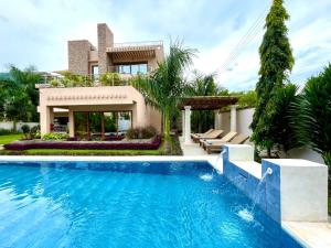 une villa avec une piscine en face d'une maison dans l'établissement Kwetu Luxury Villas, à Diani Beach