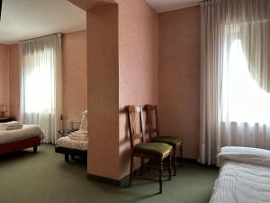 a room with two beds and two chairs and a window at Hotel Alpi - Foza in Foza
