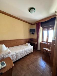 a bedroom with a bed and a desk and window at Hotel Alpi - Foza in Foza