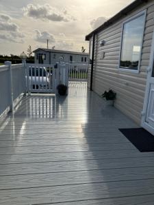 a wooden deck with a house and a building at Miss Grace Plot 26 in Ingoldmells