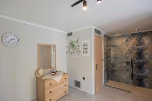 a bathroom with a sink and a clock on the wall at Villa Ilianthi in Kalamitsi +58 photos