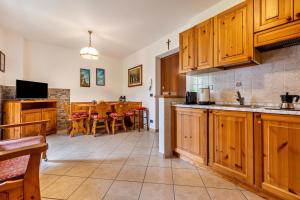 a kitchen with wooden cabinets and a dining room at Appartamento Collini Le Betulle in Spiazzo
