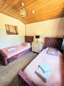 two beds in a room with a wooden ceiling at Magpie 3 HuntersMoon-Longleat-Warminster-Bath in Warminster